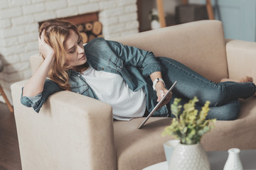 Pleasant young woman reading electronic book