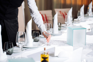 Waiter serving table in the restaurant preparing to receive guests.