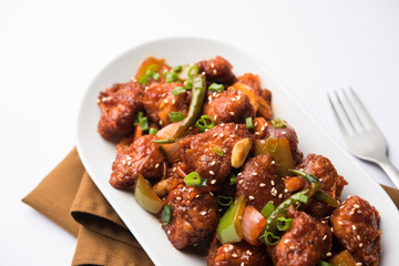 Indian Chilli Chicken dry, served in a plate over moody background. Selective focus