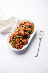 Indian Chilli Chicken dry, served in a plate over moody background. Selective focus