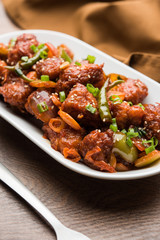 Indian Chilli Chicken dry, served in a plate over moody background. Selective focus
