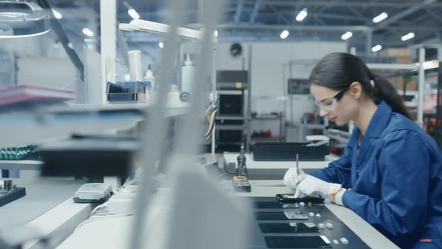 Time Lapse of Young and Senior Electronics Factory Workers in Blue and White Work Coats Using Pliers and Tweezers to Assemble Printed Circuit Boards for Smartphones. High Tech Factory Facility. 