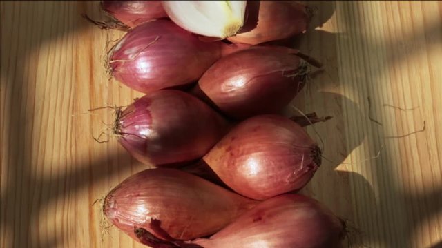 A group of shallots on a wooden board ,one half bulb is open and bright lighted ,