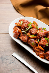 Indian Chilli Chicken dry, served in a plate over moody background. Selective focus