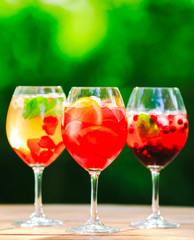 Summer cocktail. Fruit cocktail on green background. Citrus fruits, berries, strawberries, blueberries, mint, ice.