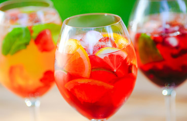 Summer cocktail. Fruit cocktail on green background. Citrus fruits, berries, strawberries, blueberries, mint, ice.