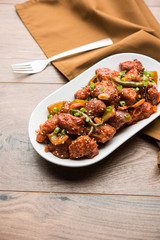 Indian Chilli Chicken dry, served in a plate over moody background. Selective focus