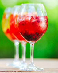 Summer cocktail. Fruit cocktail on green background. Citrus fruits, berries, strawberries, blueberries, mint, ice.