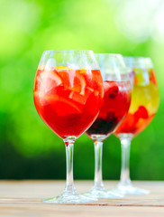Summer cocktail. Fruit cocktail on green background. Citrus fruits, berries, strawberries, blueberries, mint, ice.
