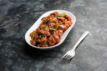 Indian Chilli Chicken dry, served in a plate over moody background. Selective focus