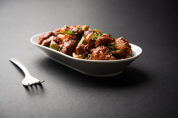 Indian Chilli Chicken dry, served in a plate over moody background. Selective focus