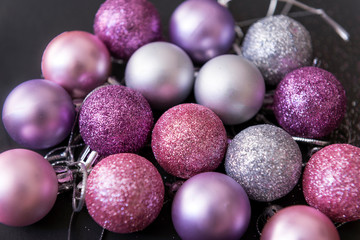 lot of pink and silver Christmas balls on a black background, Christmas decorations, top view