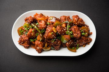 Indian Chilli Chicken dry, served in a plate over moody background. Selective focus
