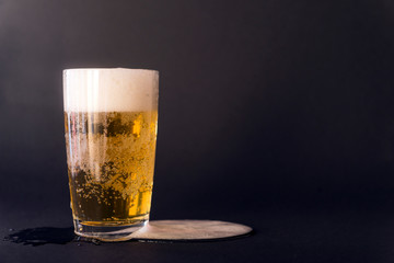 light beer in a glass on a black background, alcoholic drink