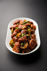 Indian Chilli Chicken dry, served in a plate over moody background. Selective focus