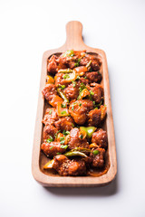 Indian Chilli Chicken dry, served in a plate over moody background. Selective focus