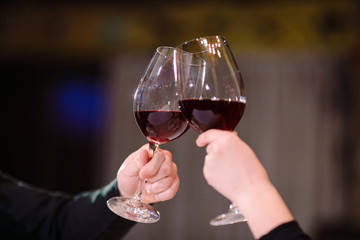 Man and woman drinking red wine. In the picture, close-up hands with glasses.