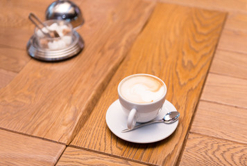 Cup of coffee on a wooden table, sugar bowl, cappuccino