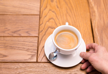man's hand holding a Cup of coffee on a saucer