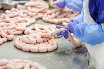 Butchers processing sausages at meat factory.