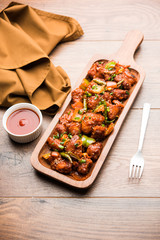 Indian Chilli Chicken dry, served in a plate over moody background. Selective focus