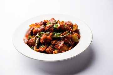 Indian Chilli Chicken dry, served in a plate over moody background. Selective focus