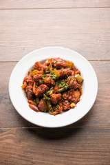 Indian Chilli Chicken dry, served in a plate over moody background. Selective focus