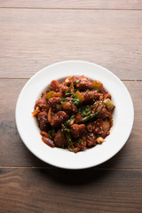 Indian Chilli Chicken dry, served in a plate over moody background. Selective focus