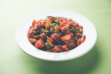 Indian Chilli Chicken dry, served in a plate over moody background. Selective focus