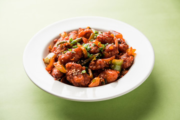 Indian Chilli Chicken dry, served in a plate over moody background. Selective focus