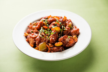 Indian Chilli Chicken dry, served in a plate over moody background. Selective focus