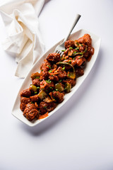 Indian Chilli Chicken dry, served in a plate over moody background. Selective focus