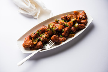 Indian Chilli Chicken dry, served in a plate over moody background. Selective focus