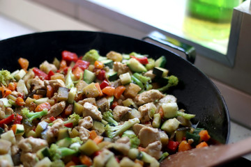 Cooking various vegetables and chicken in wok. Selective focus.