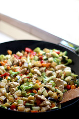 Cooking various vegetables and chicken in wok. Selective focus.
