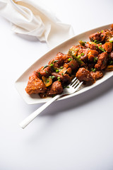 Indian Chilli Chicken dry, served in a plate over moody background. Selective focus