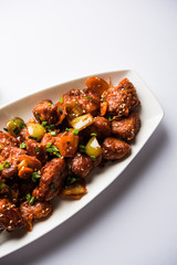 Indian Chilli Chicken dry, served in a plate over moody background. Selective focus