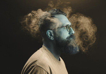 Concept. Smoke enveloped the head man. Portrait of a Bearded, stylish man with smoke. Secondhand smoke.