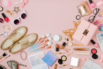 Flat lay of female fashion accessories, makeup products and handbag on pastel color background. Beauty and fashion concept