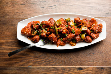 Indian Chilli Chicken dry, served in a plate over moody background. Selective focus