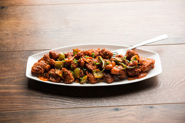 Indian Chilli Chicken dry, served in a plate over moody background. Selective focus