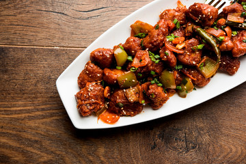 Indian Chilli Chicken dry, served in a plate over moody background. Selective focus