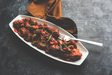 Indian Chilli Chicken dry, served in a plate over moody background. Selective focus