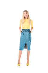 smiling attractive woman standing in yellow shirt and denim skirt and looking at camera isolated on white