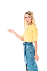 smiling attractive woman in yellow shirt showing something and looking at camera isolated on white