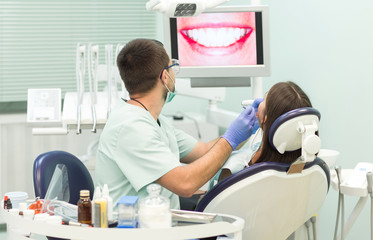 young woman sitting in the dentist's chair with opened mouth at dentist's office while having examination.