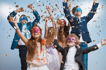 Adorable kids have fun together throw colourful confetti at birthday party. They playing together in different games, spending time in decorated studio. Children and events concept