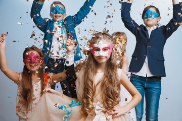 Adorable kids have fun together throw colourful confetti at birthday party. They playing together...