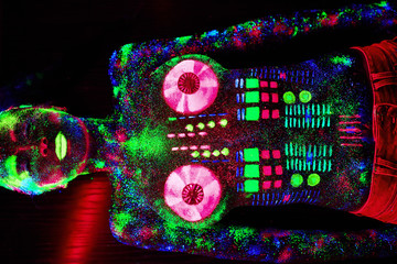 Concept. On the body of a girl painted DJ deck. Half-naked girl painted in UV colors.
