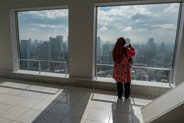 Unidentified Muslim tourist woman takes a photo of Osaka skyline from Umeda sky building in Osaka,...